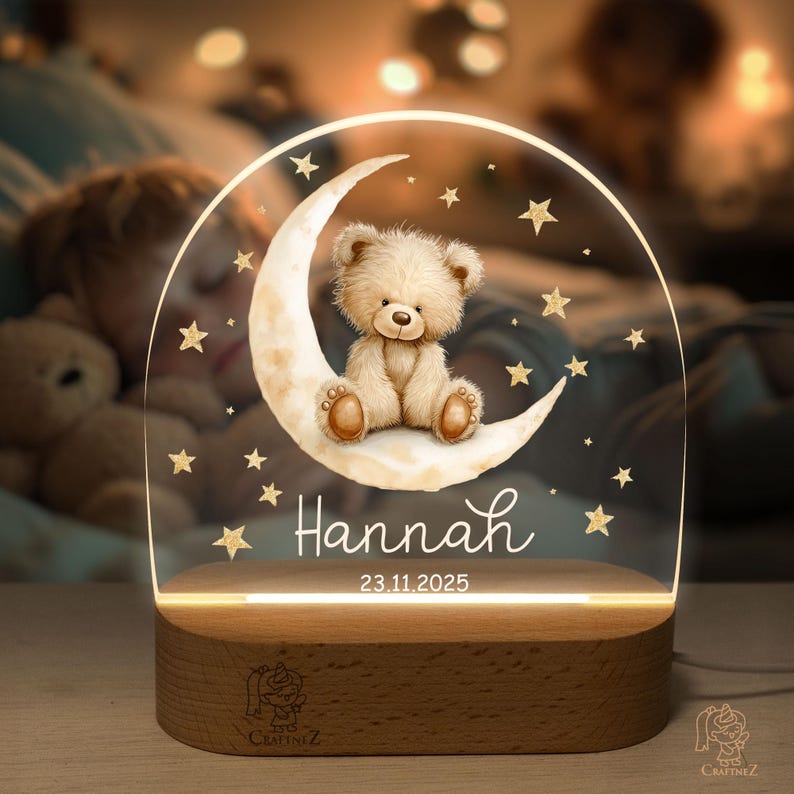 A teddy bear sitting on a crescent moon, surrounded by stars, is the central focus of the image. The name "Hannah" is written below the crescent moon, and the date "23.11.2025" is displayed below the bear.