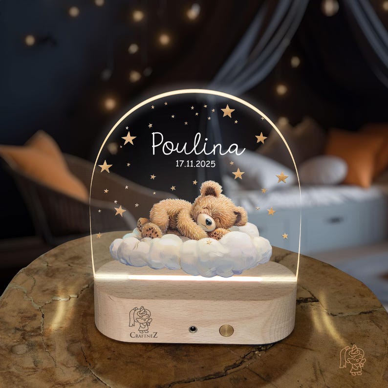 A wooden nightstand with a clear glass display case on top, featuring a teddy bear sleeping on a cloud and the name "Poulina" written on the display.