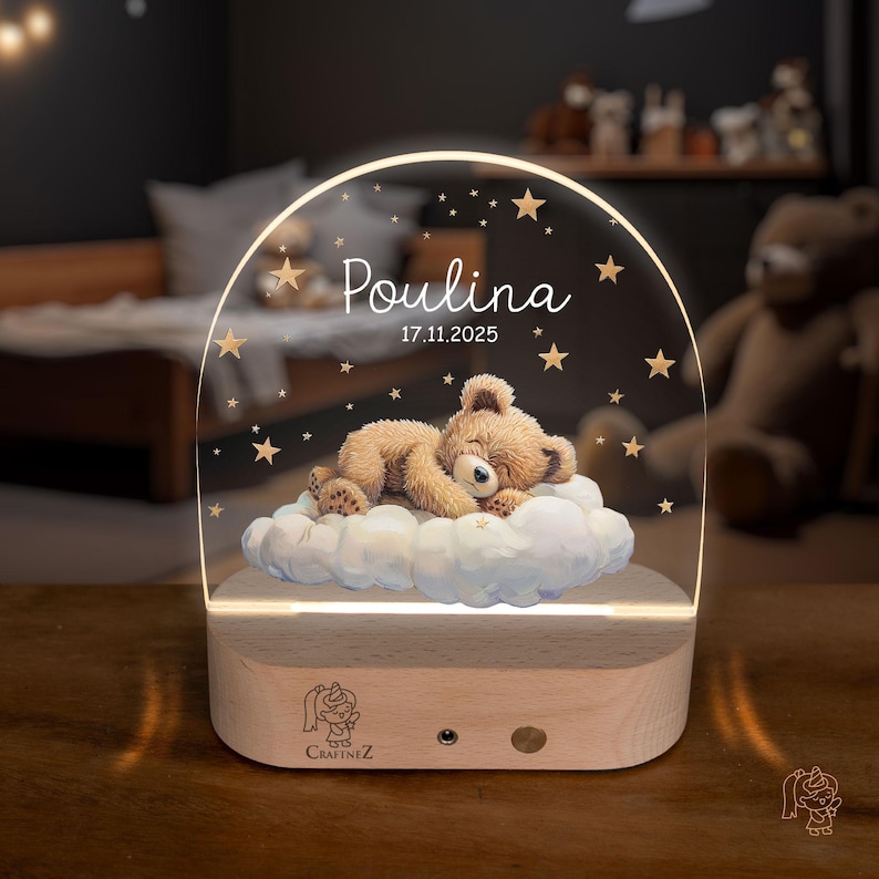 A wooden nightstand with a glass display case containing a teddy bear sleeping on a cloud, surrounded by stars. The display case has a name and date printed on it.