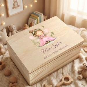 Puede incluir: Una caja de recuerdos rectangular de madera clara con una ilustración impresa de un hada con corona de flores y vestido rosa. El texto Mia-Sophie, 22.11.2025 - 11:25 Uhr - 3100g - 49 cm está impreso en una fuente cursiva oscura.