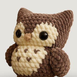 Peut inclure: Une peluche hibou au crochet faite à la main, de couleurs marron et crème. Le hibou a de grands yeux noirs, un petit bec et de la laine texturée et moelleuse. Les ailes et le corps sont détaillés avec une texture douce et câline, idéale pour une chambre d'enfant.