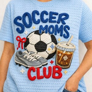 May include: Light blue crochet t-shirt with the words "SOCCER MOMS CLUB" in blue and red. The shirt features a soccer ball, a pair of soccer cleats, and a coffee drink, all in crochet.