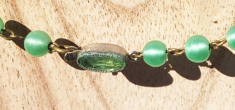 K&ouml;nnte beinhalten: Eine Halskette aus gr&uuml;nen Glasperlen mit einem Anh&auml;nger aus Silber und gr&uuml;nem Glas.