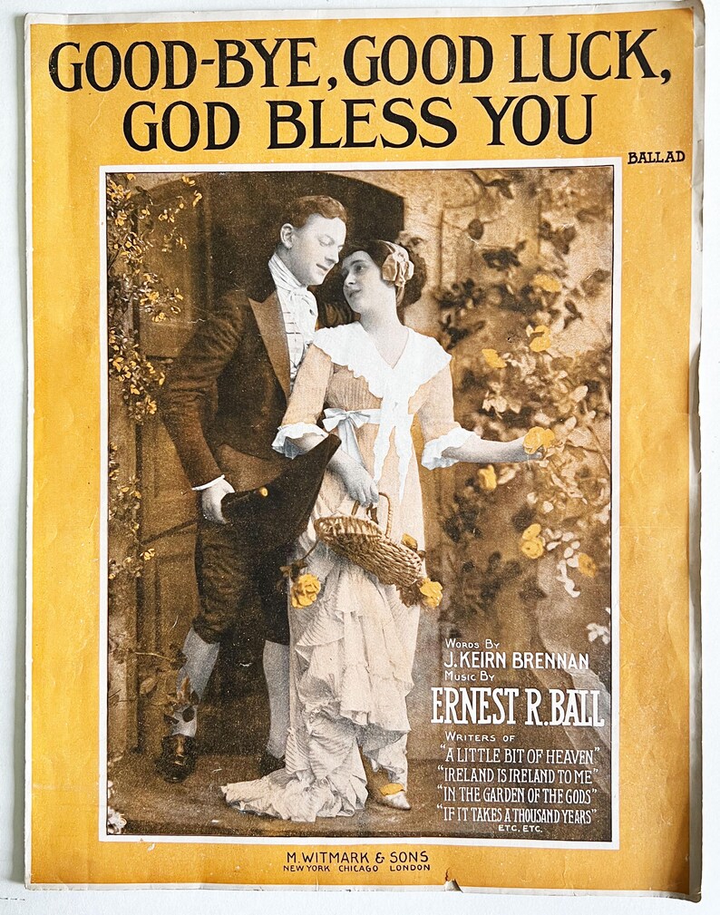 May include: A vintage sheet music cover featuring a couple in a garden setting. The cover is yellow with black text that reads "Good-Bye, Good Luck, God Bless You." The text "BALLAD" is in the upper right corner. The text "Words by J. Keirn Brennan Music by Ernest R. Ball" is in the lower right corner. The text "Writers of "A Little Bit of Heaven" "Ireland is Ireland to Me" "In the Garden of the Gods" "If it Takes a Thousand Years" ETC. ETC." is in the lower right corner. The text "M. Witmark & Sons New York Chicago London" is in the lower left corner.