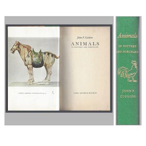 May include: A hardcover book titled Animals in Pottery and Porcelain by John P. Cushion, featuring a green spine with gold lettering and a rooster illustration, and an open page showing a horse figurine with a saddle and the text Cory, Adams & Mackay.