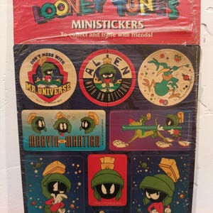 Puede incluir: Una hoja de mini pegatinas de Looney Tunes con Marvin el Marciano. Las pegatinas muestran a Marvin en varias poses y diseños. El embalaje es rojo y azul, con las palabras "Looney Tunes" y "Ministickers" impresas. Las pegatinas están diseñadas para coleccionar e intercambiar.