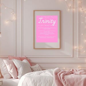 Puede incluir: Una habitación con una cama cubierta con ropa de cama blanca y una manta rosa. Un cartel rosa enmarcado con el nombre "Trinity" cuelga de la pared. La habitación está decorada con luces de cadena y una mesita de noche.