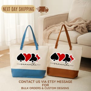 May include: Two off-white canvas tote bags featuring a graphic of four playing card suits—spade, heart, club, and diamond—above the name Samantha in black script. One bag has a blue base and handles, while the other has a brown base and handles.