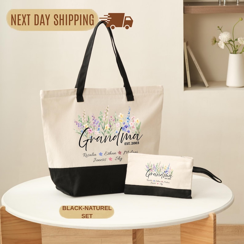 A beige tote bag with a floral design and the text "Grandma" printed on it, along with a smaller bag and a black handle, all placed on a white table.