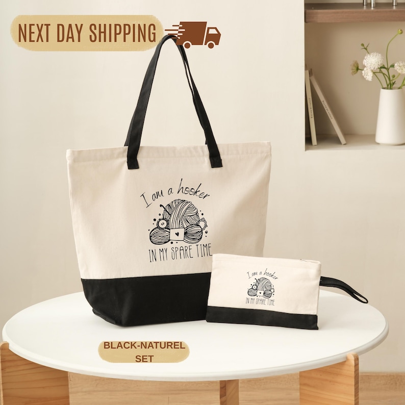 A beige tote bag with a black handle and a smaller white bag with a black handle, both featuring a humorous knitting-related design, are displayed on a white table.
