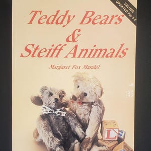 May include: A book titled "Teddy Bears & Steiff Animals" by Margaret Fox Mandel. The cover features two vintage teddy bears and wooden alphabet blocks. The book is a full-color identification and value guide.