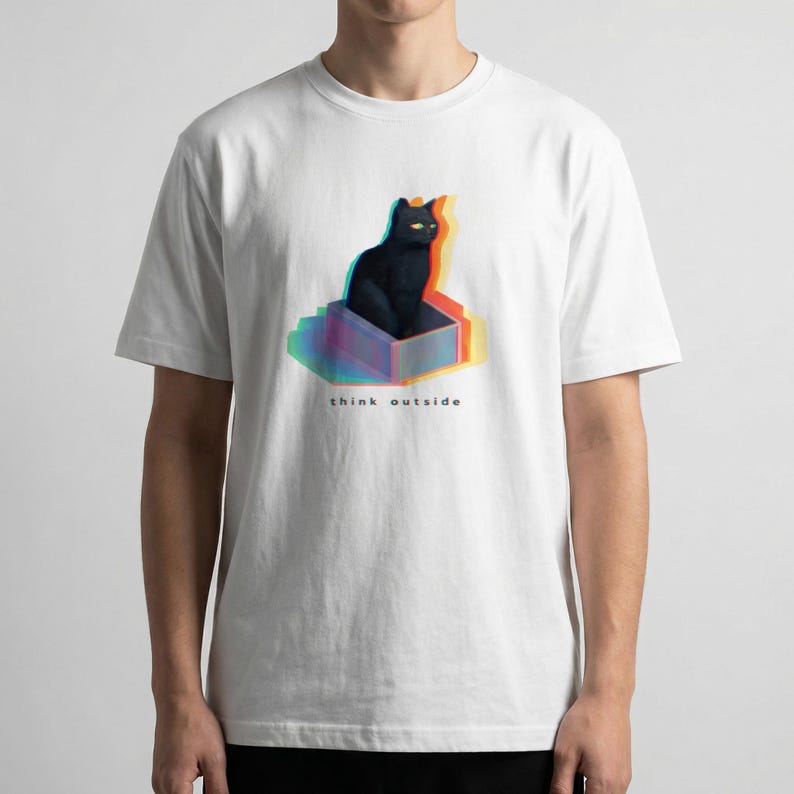 Puede incluir: Camiseta blanca con una ilustraci&oacute;n de un gato negro dentro de una caja con efecto 3D. El gato tiene ojos amarillos y el texto "think outside" est&aacute; debajo. El dise&ntilde;o tiene un efecto colorido y en capas.