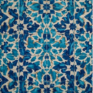 May include: A close-up of a tiled surface with a repeating floral pattern. The design features blue and turquoise floral shapes against a beige background. The tiles are arranged in a grid, creating a cohesive and decorative surface.