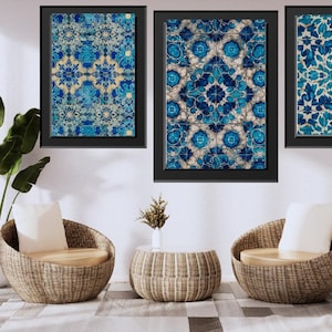 May include: Three framed wall art pieces with blue and white floral patterns hang above two wicker chairs with cream cushions. A small round table and a potted plant complete the room's decor. The room has a modern, minimalist aesthetic.