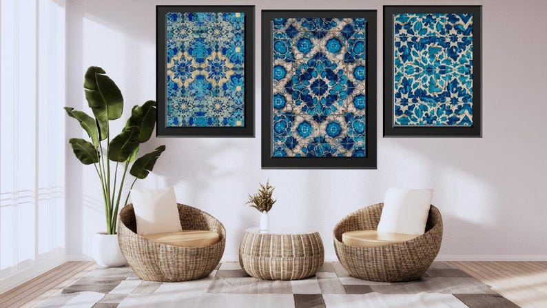 May include: Three framed wall art pieces with blue and white floral patterns hang above two wicker chairs with cream cushions. A small round table and a potted plant complete the room's decor. The room has a modern, minimalist aesthetic.