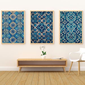 May include: Three framed wall art pieces with intricate blue and white floral patterns. The artwork is displayed on a white wall above a wooden console table. The frames are a light wood color.