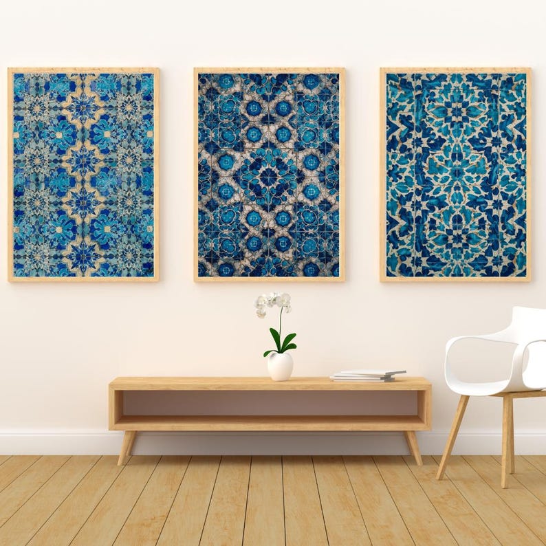 May include: Three framed wall art pieces with intricate blue and white floral patterns. The artwork is displayed on a white wall above a wooden console table. The frames are a light wood color.