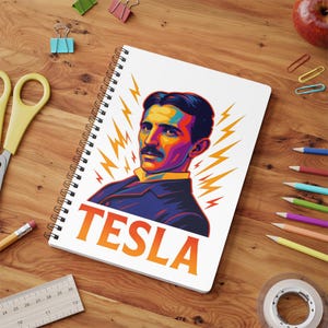 May include: A spiral-bound notebook with a vibrant portrait of Nikola Tesla and lightning bolt designs. The word "TESLA" is printed in orange and white. The notebook is on a wooden desk with stationery items.