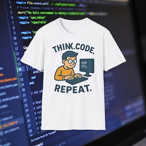 Op de afbeelding: Wit t-shirt met een cartoonafbeelding van een persoon die op een computer codeert. De tekst op het shirt luidt "THINK.CODE. REPEAT." De persoon in de afbeelding draagt een bril en een oranje shirt. De achtergrond toont computercode.