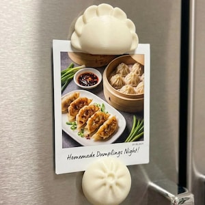 Könnte beinhalten: Ein rechteckiger Fotodruck mit einem Teller gebratener Teigtaschen, einem Bambusdämpfer mit Suppen-Teigtaschen und einer kleinen Schale mit Dip-Sauce. Der Text "Homemade Dumplings Night!" steht unten. Zwei cremeweiße Magnete in Teigtaschenform.
