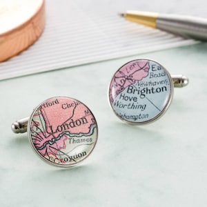 Puede incluir: Un par de gemelos de plata con diseños de mapas vintage. Un gemelo presenta un mapa de Londres con el río Támesis y las palabras "Londres", "Thames" y "Croydon". El otro gemelo presenta un mapa de Brighton con las palabras "Brighton", "Hove", "Worthing" y "Newhaven".