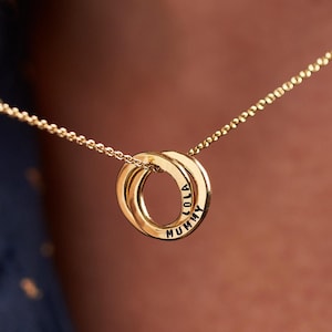 May include: Gold necklace with two interlocking rings. The rings are engraved with the names "Mummy" and "Lola".