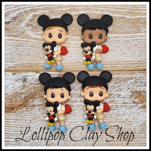 May include: Four clay figurines of a boy wearing a black Mickey Mouse hat, holding a Mickey Mouse toy. The boy is wearing a white shirt, khaki shorts, red backpack, and blue shoes. The text "Lollipop Clay Shop" is at the bottom.