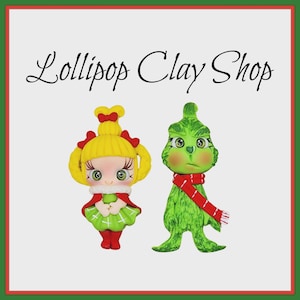 May include: Two clay figurines: a girl with yellow hair and a green dress, and a green Grinch figure wearing a red scarf. The text "Lollipop Clay Shop" is written above the figurines in a cursive font. The figures are set against a white background with a red and green border.