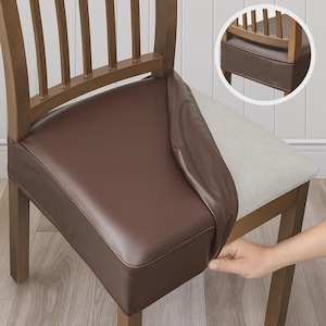 Può includere: Una fodera per sedile di sedia in pelle marrone viene posizionata su una sedia di legno. La fodera è di un marrone scuro intenso e sembra essere realizzata in un materiale liscio e resistente. La sedia ha un sedile in tessuto colorato chiaro sotto.