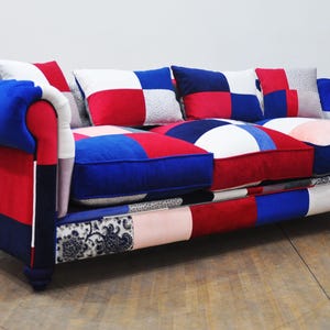 May include: A patchwork sofa with red, blue and white fabric. The sofa has a tufted back and rolled arms.