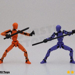 May include: Two articulated action figures in a martial arts pose. One figure is orange and the other is purple. Each figure holds a black weapon. The figures are on a white background.