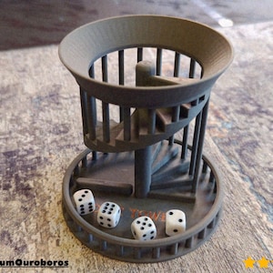 May include: A gray dice tower with a spiral staircase design. Four white dice with black dots are in the base of the tower. The text "Dice Tower" is visible. The tower is made of a textured material.