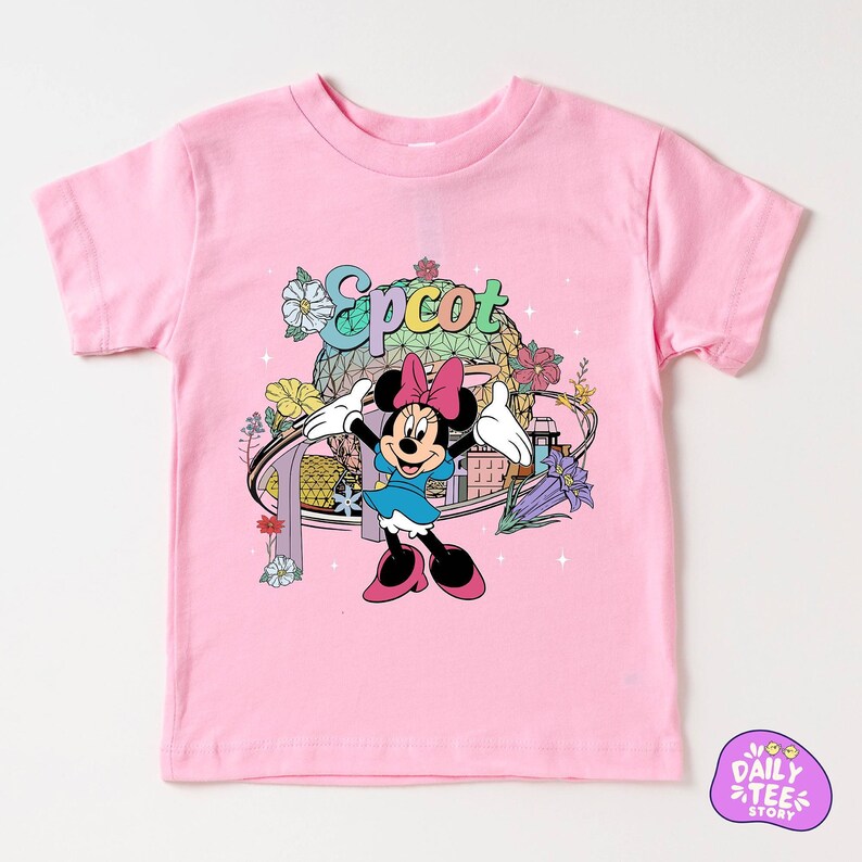 A pink t-shirt with a Minnie Mouse character and various colorful elements, such as flowers and a globe, printed on it.