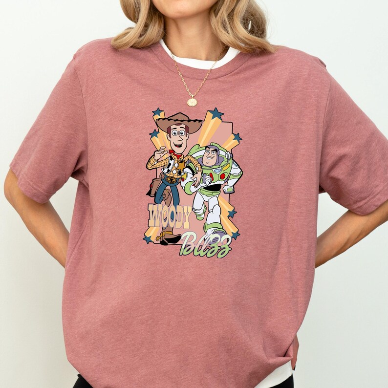 A woman wearing a pink t-shirt with a graphic of Woody and Buzz Lightyear from the Toy Story movie.