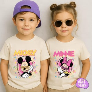 Two children wearing Mickey Mouse t-shirts and sunglasses, smiling at the camera.