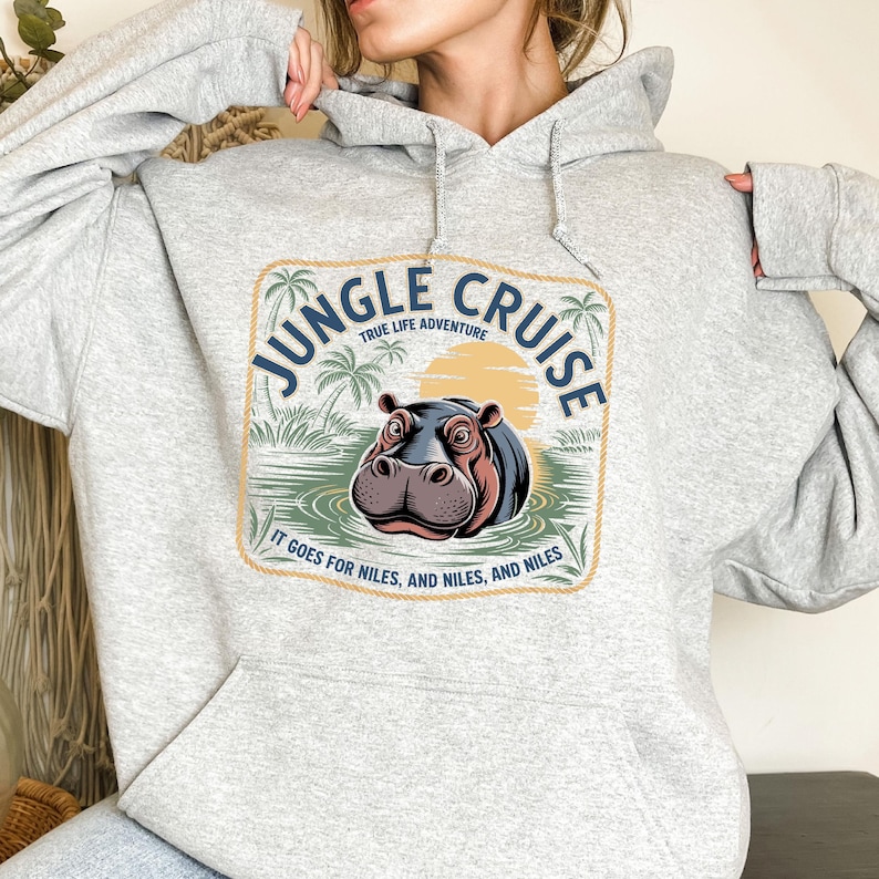 A gray hoodie with a graphic design featuring a hippopotamus and the text "JUNGLE CRUISE" and "IT GOES FOR MILES, AND MILES, AND MILES" printed on it.