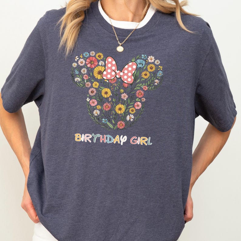 A person wearing a gray t-shirt with a graphic design of a flowery Minnie Mouse and the text "BIRTHDAY GIRL" printed on it.