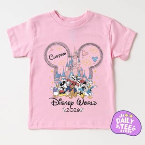 A pink t-shirt with a Disney World-themed graphic design featuring Mickey Mouse, Donald Duck, and other Disney characters.