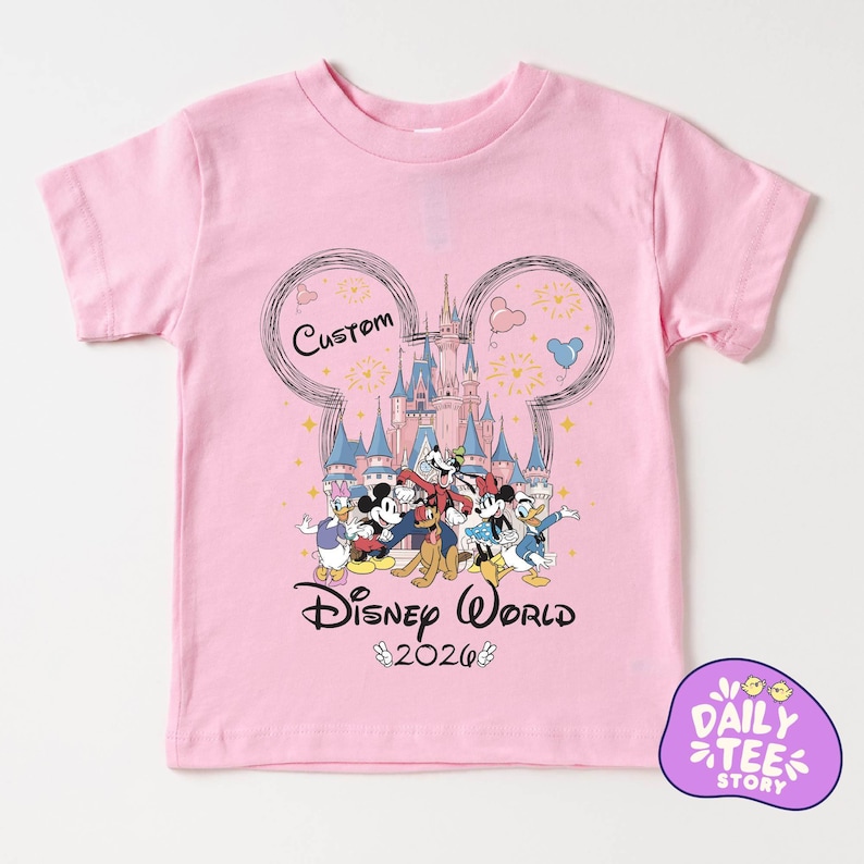 A pink t-shirt with a Disney World-themed graphic design featuring Mickey Mouse, Donald Duck, and other Disney characters.