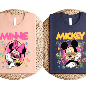 two t-shirts with the characters Minnie Mouse and Mickey Mouse printed on them.