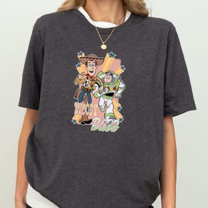 A gray t-shirt with a graphic design featuring characters from the Toy Story movie, including Woody and Buzz Lightyear.