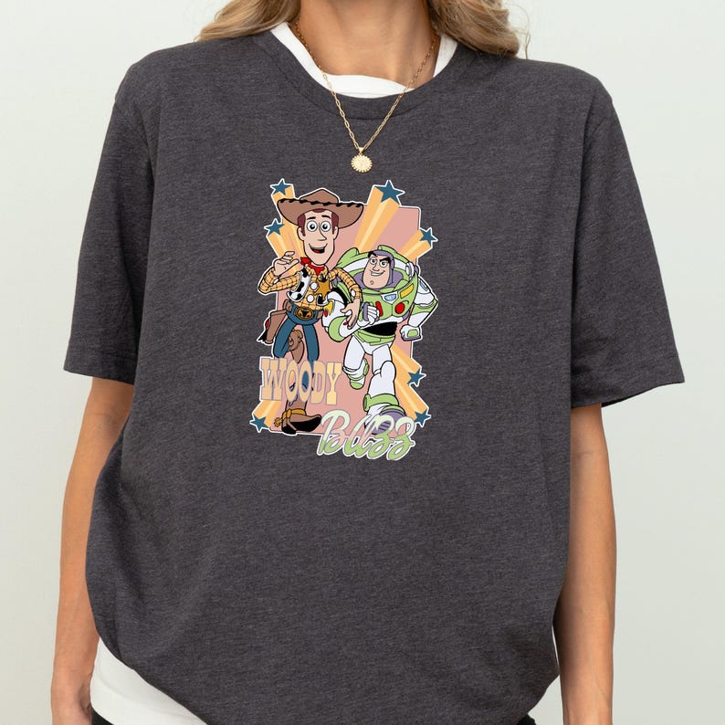 A gray t-shirt with a graphic design featuring characters from the Toy Story movie, including Woody and Buzz Lightyear.