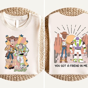 two t-shirts with cartoon characters from the Toy Story franchise. The t-shirt on the left features Woody and Buzz Lightyear, while the t-shirt on the right shows Buzz Lightyear and Woody. Both t-shirts have the text "You got a friend in me" printed on them.