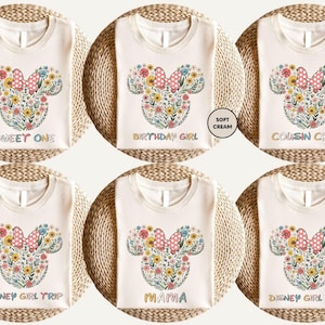 The image is a collage of six white t-shirts with a floral design and text printed on them.