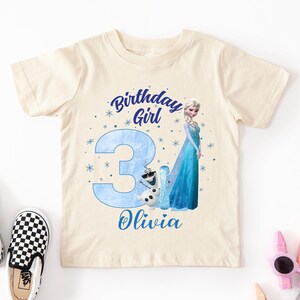 A white t-shirt with a birthday girl design and the number 3 printed on it, along with a character from the Disney movie Frozen.