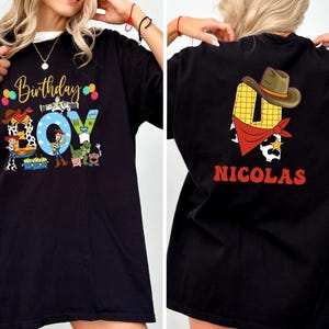 a person wearing a black t-shirt with a colorful graphic design on the front and a personalized name on the back.