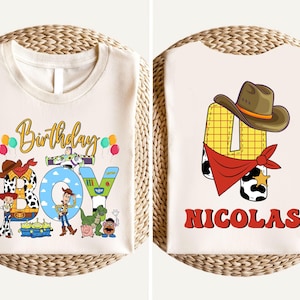 two white t-shirts with cartoon characters and text, likely representing a birthday theme. The t-shirt on the left has a collage of characters and text, while the t-shirt on the right features a single character and the name "Nicolas" written below it.
