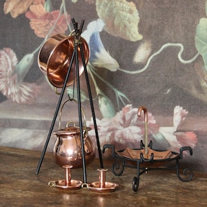 Puede incluir: Colección de objetos decorativos en miniatura de cobre y metal negro. Incluye una olla de cobre sobre trípode, una pequeña tetera de cobre, dos candelabros y un plato decorativo en forma de paraguas.