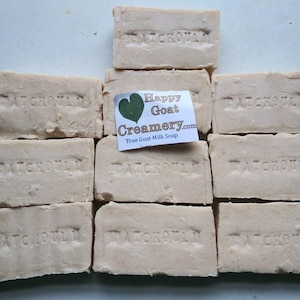 May include: A collection of light beige rectangular bars of soap, each stamped with the word "PATCHOULI". A small label reads "Happy Goat Creamery.com True Goat Milk Soap". The soaps are arranged closely together.