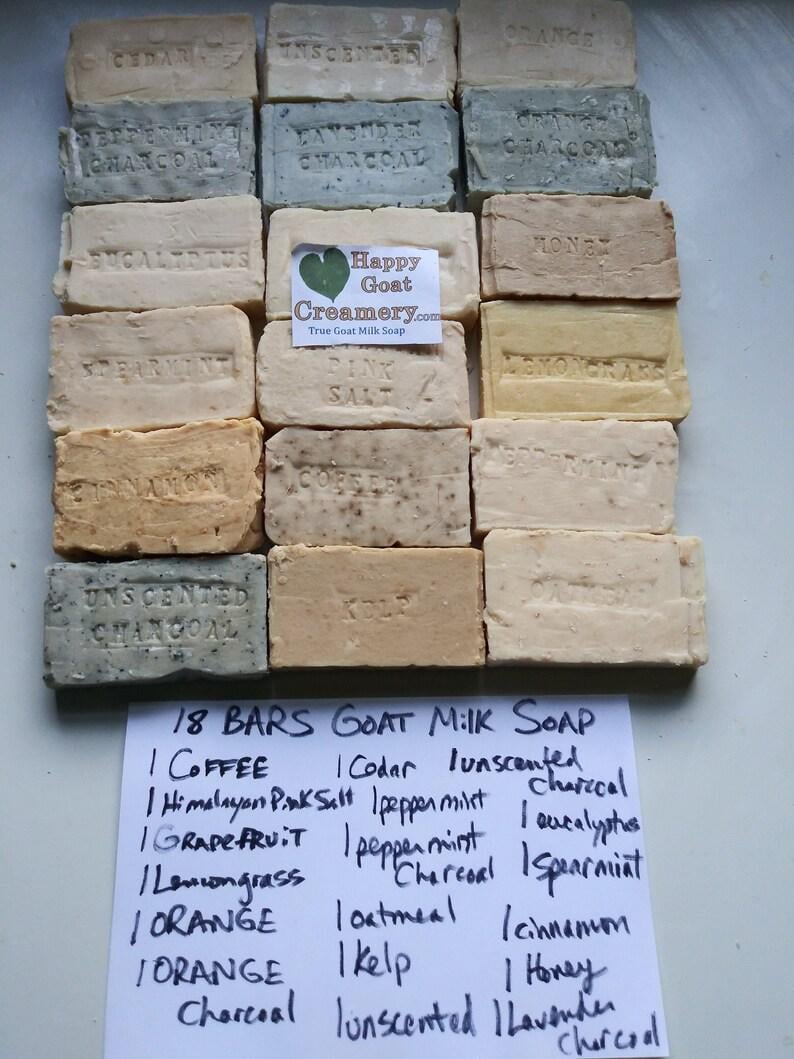 May include: An assortment of 18 bars of goat milk soap in various colors and scents, including charcoal, lavender, and coffee. The bars are rectangular and stamped with the scent name. A handwritten list details the soap varieties.